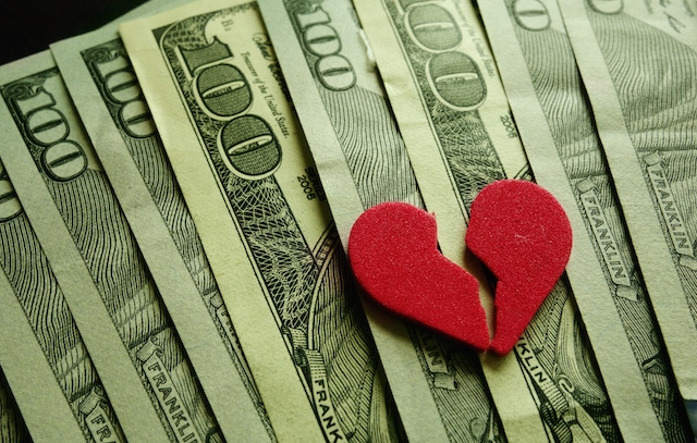 Broken red heart on assorted cash